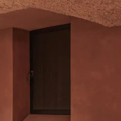 Nis met donkere deur in de terracotta wand onder een gestructureerd plafond, Hoeve in Westkapelle, interieur Laura Calleeuw