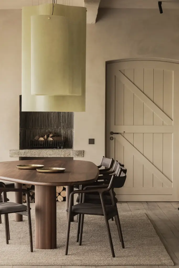 Open haard met houtstapel, eettafel en een wit gelatteerde deur, Hoeve in Westkapelle, interieur Laura Calleeuw