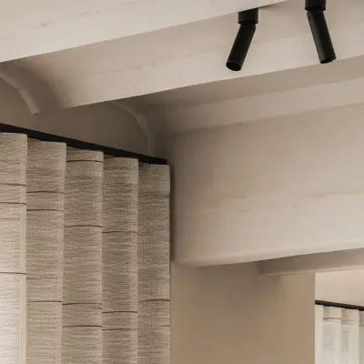 Gekalkte plafondbalken met zwarte spots en een gepleisterde schouw naast een gordijn, Hoeve in Westkapelle, interieur Laura Calleeuw