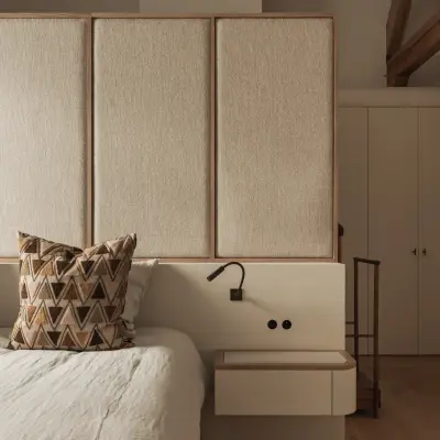 Slaapkamer met hoog gestoffeerd hoofdbord in linnen, leeslampjes en kussens met grafisch patroon, Hoeve in Westkapelle, interieur Laura Calleeuw