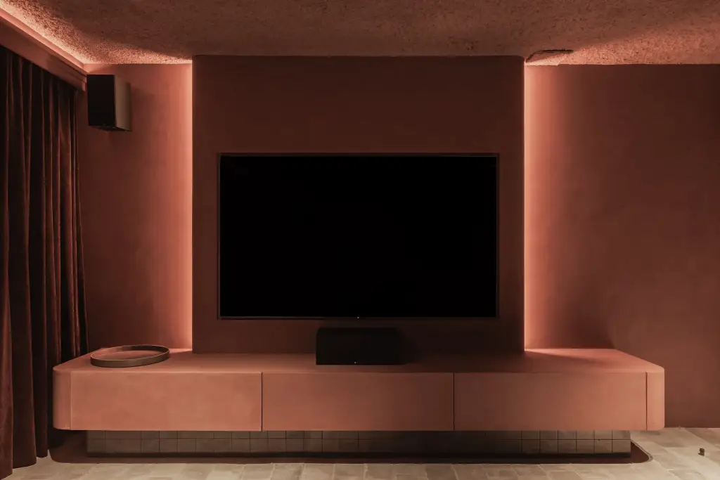 Televisie boven een zwevend terracotta meubel tussen fluwelen gordijnen, Hoeve in Westkapelle, interieur Laura Calleeuw