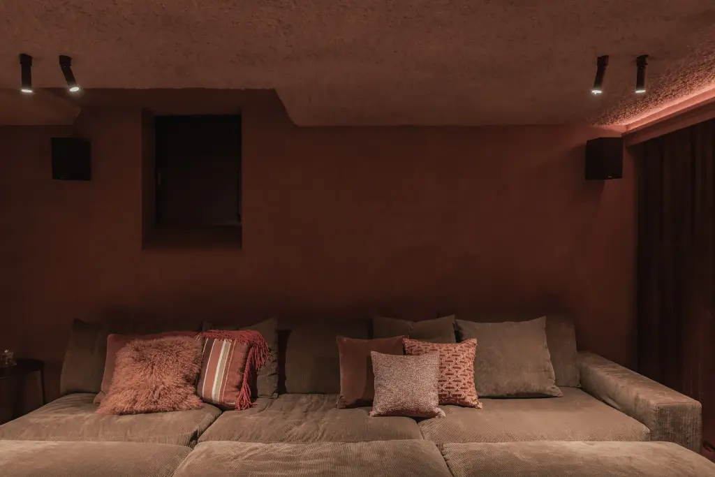 Thuisbioscoop met brede zetel, kussens, schapenvacht en ingebouwde luidsprekers, Hoeve in Westkapelle, interieur Laura Calleeuw