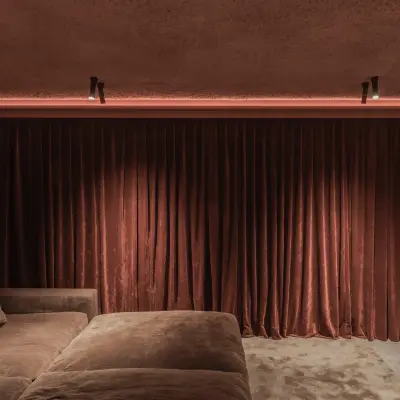 Thuisbioscoop met fluwelen gordijn, grote sofa en een lichtlijn boven het scherm, Hoeve in Westkapelle, interieur Laura Calleeuw