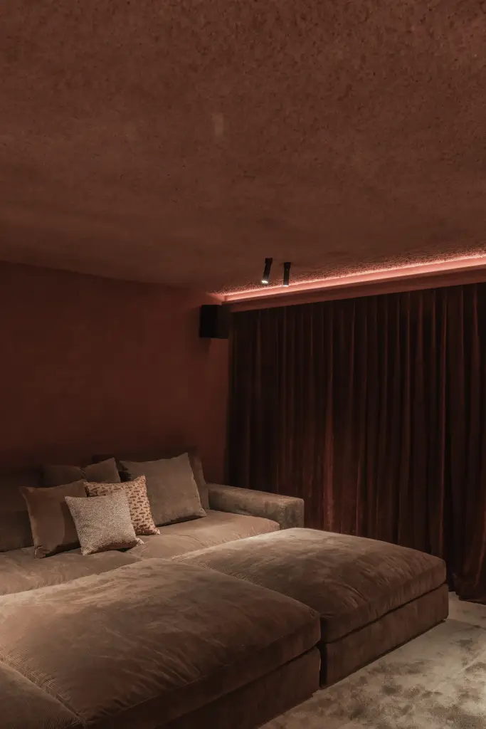 Brede zetel met kussens voor een fluwelen gordijn in de thuisbioscoop, Hoeve in Westkapelle, interieur Laura Calleeuw
