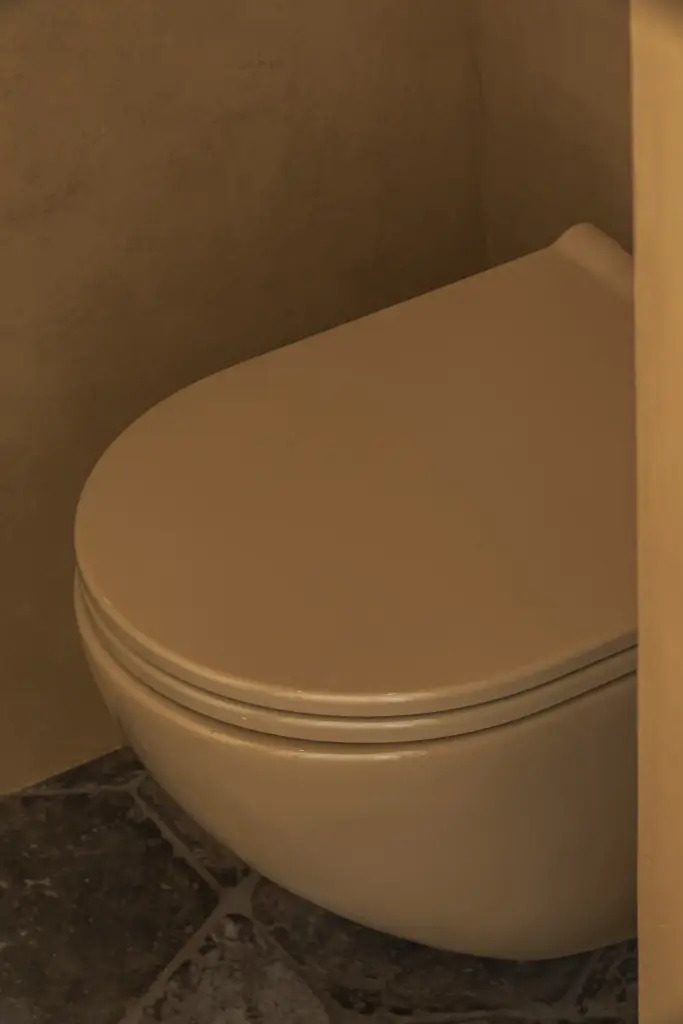 Hangtoilet in de kleur van de okergele leempleisterwand, Hoeve in Westkapelle, interieur Laura Calleeuw