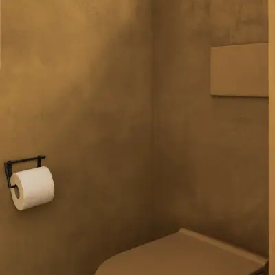 Hangtoilet in de kleur van de okergele leempleisterwand, Hoeve in Westkapelle, interieur Laura Calleeuw