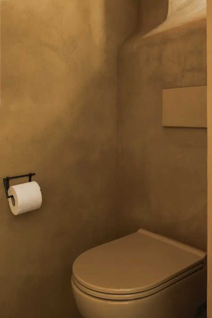 Hangtoilet in de kleur van de okergele leempleisterwand, Hoeve in Westkapelle, interieur Laura Calleeuw