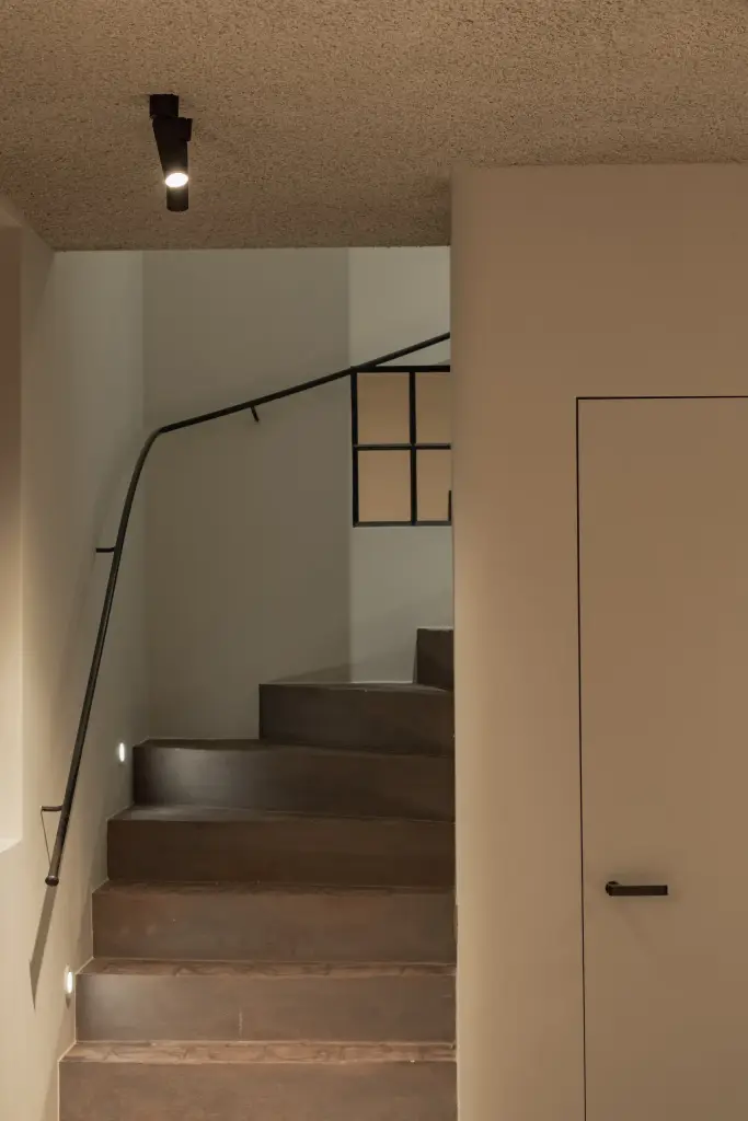 Trap naar de kelder met zwarte leuning en een inbouwspot, Hoeve in Westkapelle, interieur Laura Calleeuw