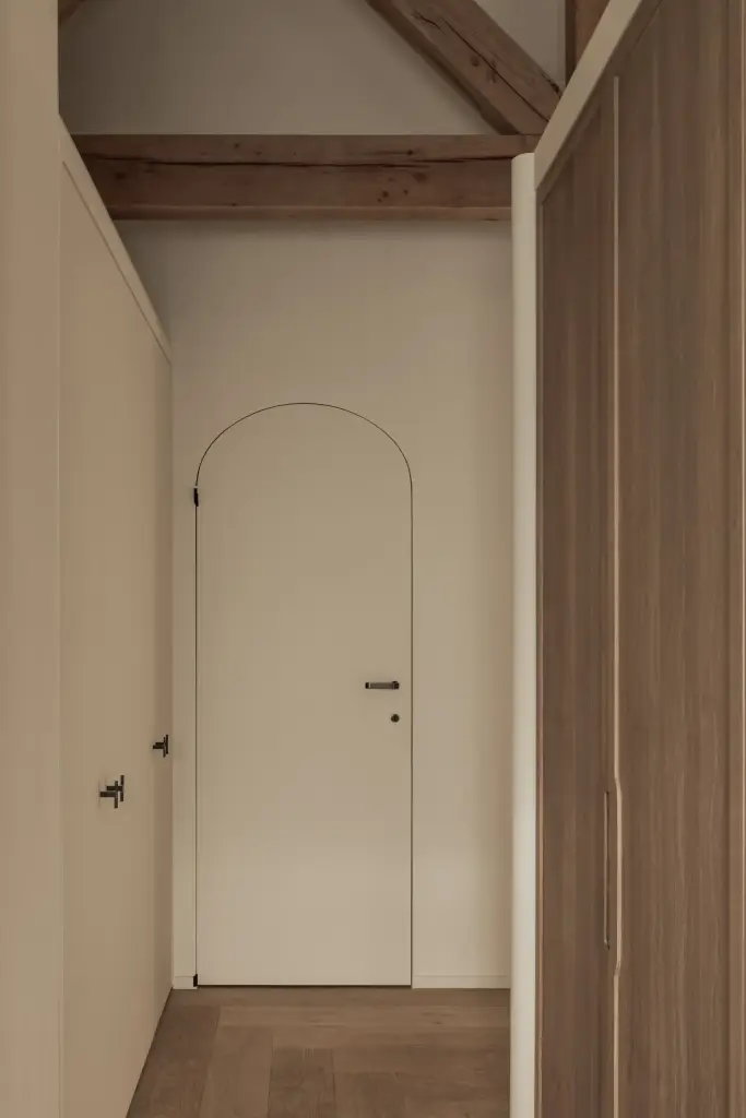 Witte boogdeur naast een kastenwand in eikenhout, Hoeve in Westkapelle, interieur Laura Calleeuw