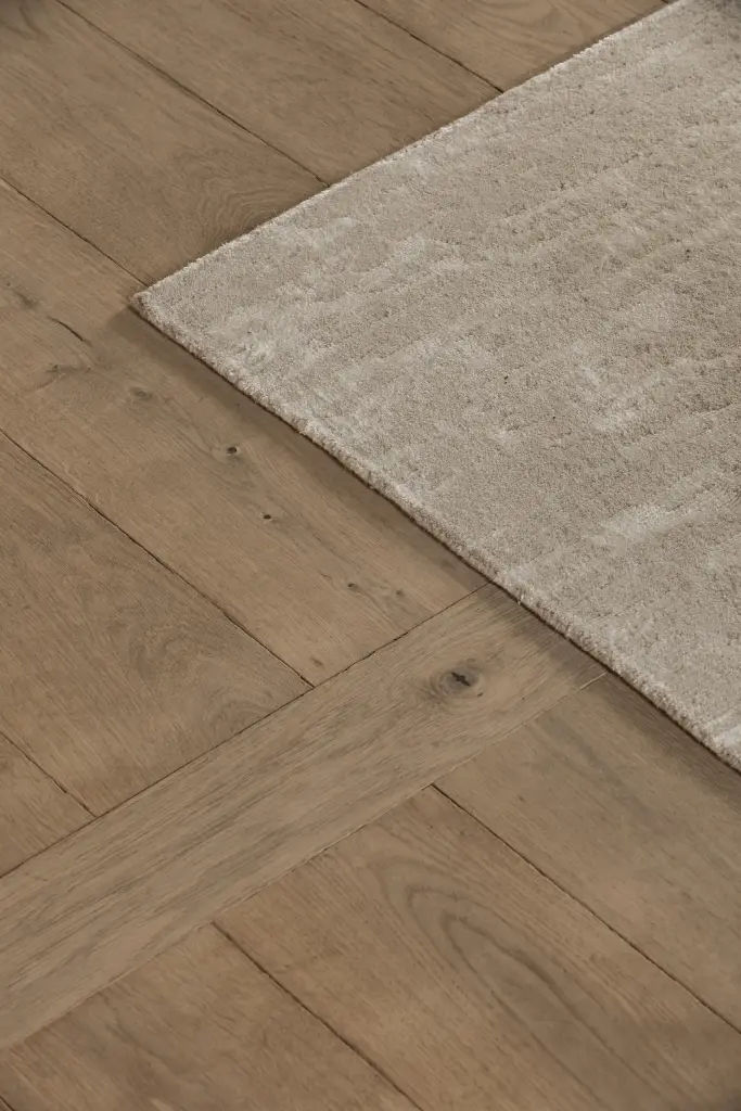 Detail van een wollen tapijt op visgraatparket, Hoeve in Westkapelle, interieur Laura Calleeuw