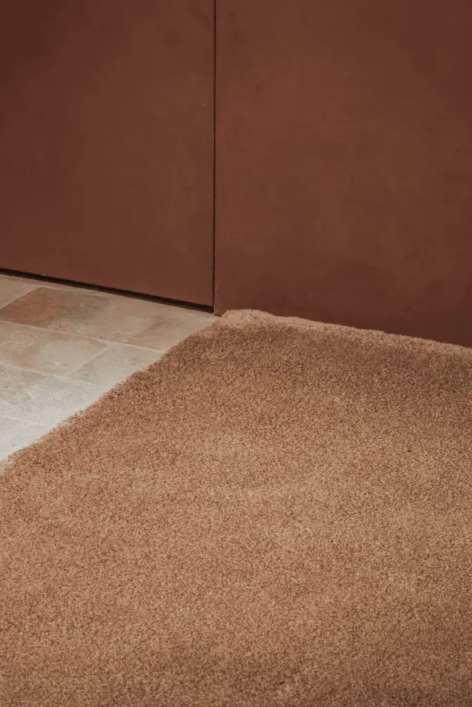 Wollen tapijt op de vloer langs de terracotta wand, Hoeve in Westkapelle, interieur Laura Calleeuw