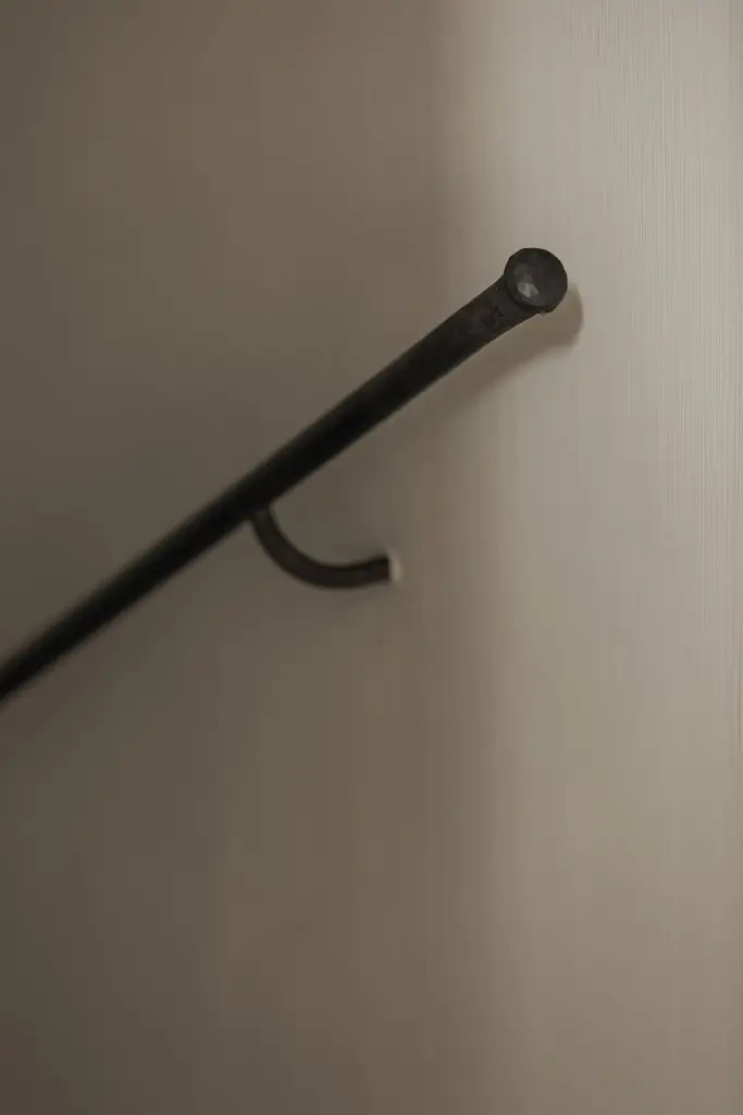 Detail van een zwarte trapleuning aan een gepleisterde wand, Hoeve in Westkapelle, interieur Laura Calleeuw