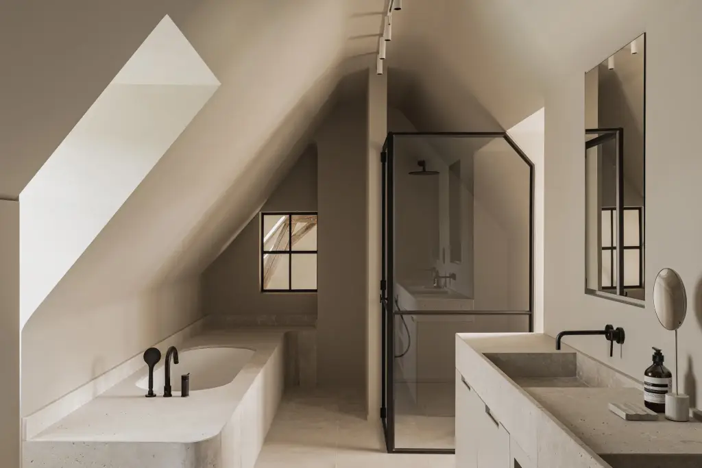 Badkamer onder de dakhelling met inbouwbad, stalen douchewand en natuurstenen wastafel, a masterful balance between authenticity and comfort, interieur Laura Calleeuw