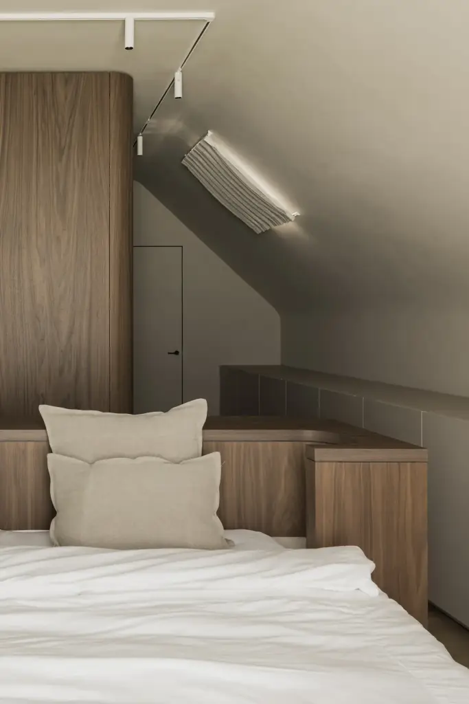 Bed met notelaren nachtkastje en leeslamp onder de dakhelling, a masterful balance between authenticity and comfort, interieur Laura Calleeuw