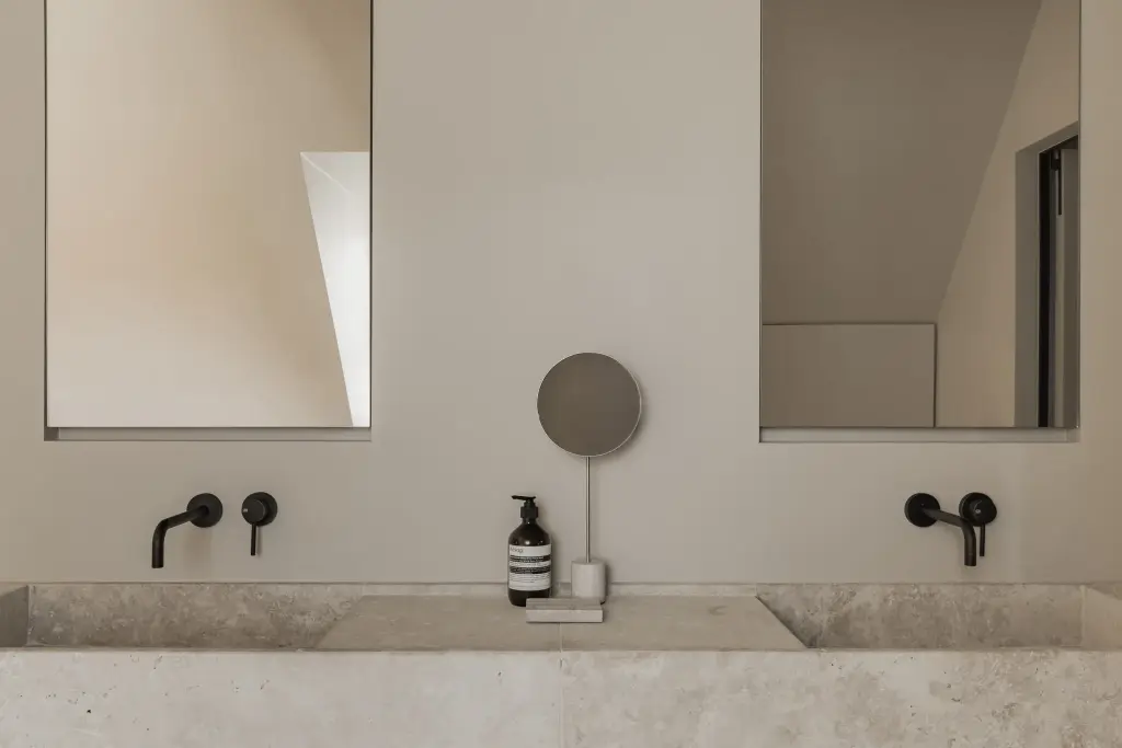 Dubbele natuurstenen wastafel met wandkranen, spiegels en een zeepdispenser, a masterful balance between authenticity and comfort, interieur Laura Calleeuw