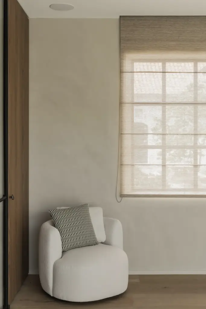 Witte fauteuil in bouclé voor een raam met roman blind, a masterful balance between authenticity and comfort, interieur Laura Calleeuw