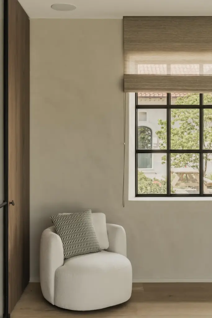 Fauteuil met kussen naast een zwart raam met roman blind, a masterful balance between authenticity and comfort, interieur Laura Calleeuw