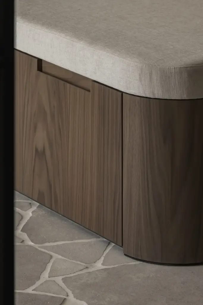 Detail van de gebogen notelaren zitbank met linnen zitting op een natuurstenen vloer, a masterful balance between authenticity and comfort, interieur Laura Calleeuw