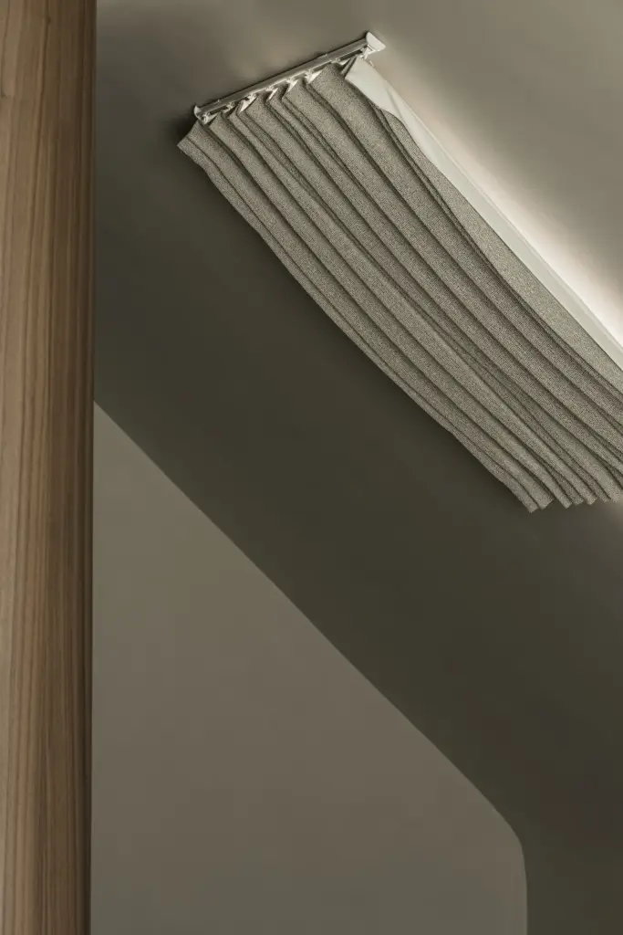 Detail van het gordijn aan de rail langs de notelaren wand onder de dakhelling, a masterful balance between authenticity and comfort, interieur Laura Calleeuw