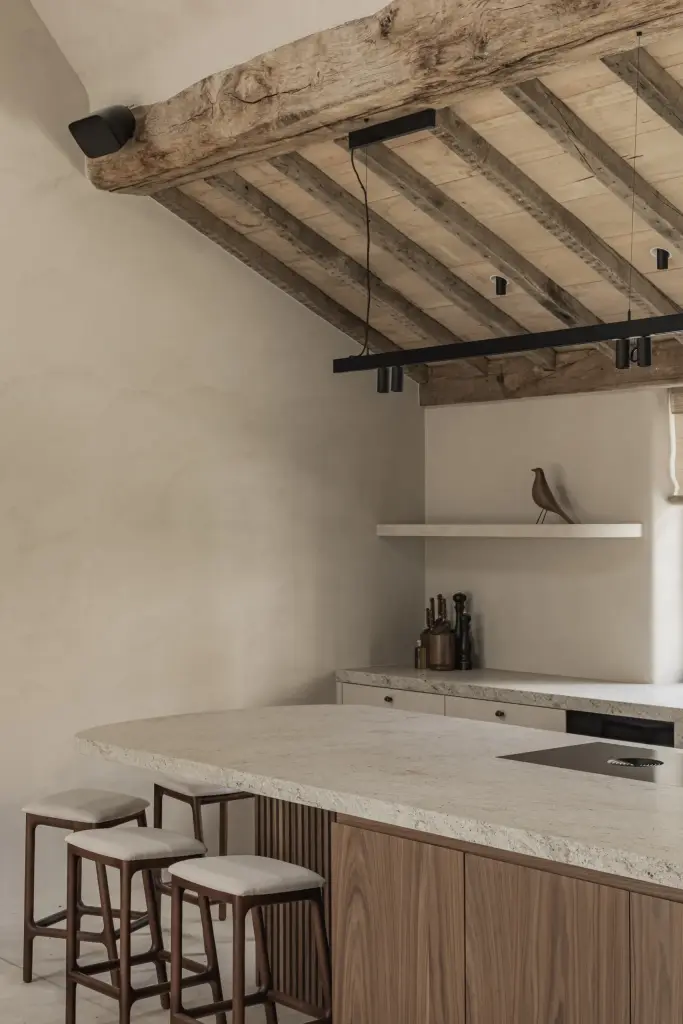 Keuken onder oude houten balken met natuurstenen kookeiland en houten krukken, a masterful balance between authenticity and comfort, interieur Laura Calleeuw