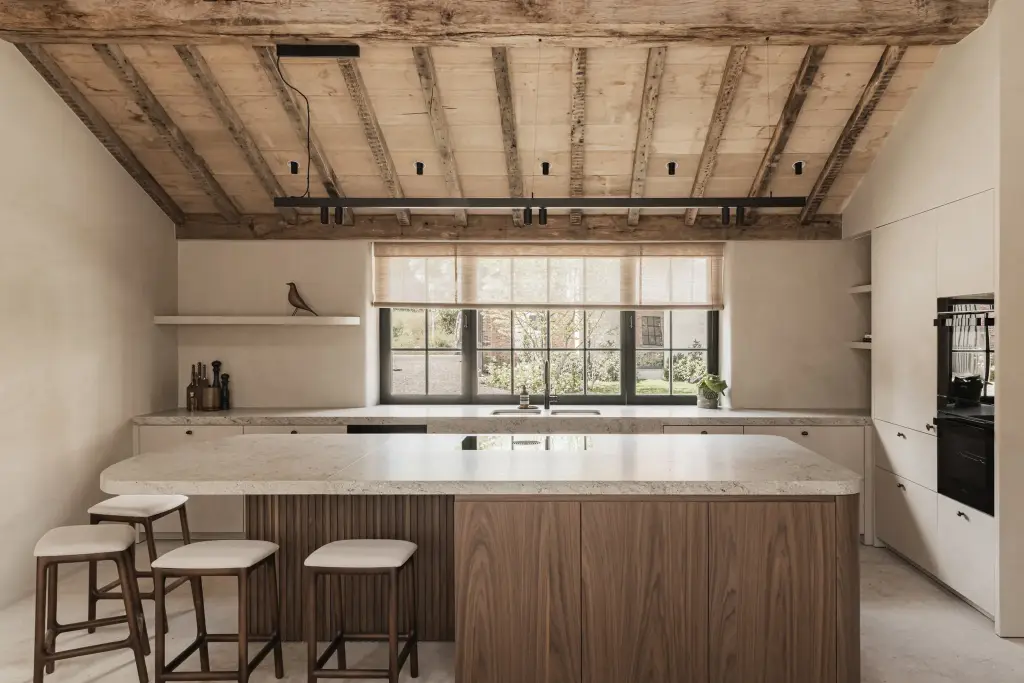 Keuken met kookeiland, ribbelfront in notelaar, inbouwoven en een raam onder oude houten balken, a masterful balance between authenticity and comfort, interieur Laura Calleeuw