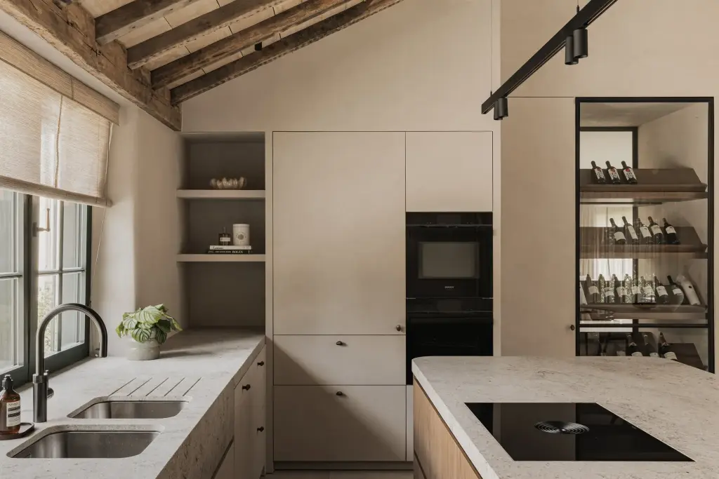 Keuken met spoelbak, zwarte kraan, kookeiland, wijnkast en oude balken, a masterful balance between authenticity and comfort, interieur Laura Calleeuw