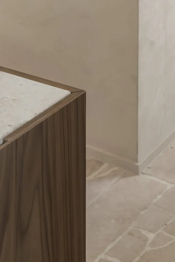 Detail van een notelaren hoek met natuurstenen blad en natuurstenen vloer, a masterful balance between authenticity and comfort, interieur Laura Calleeuw