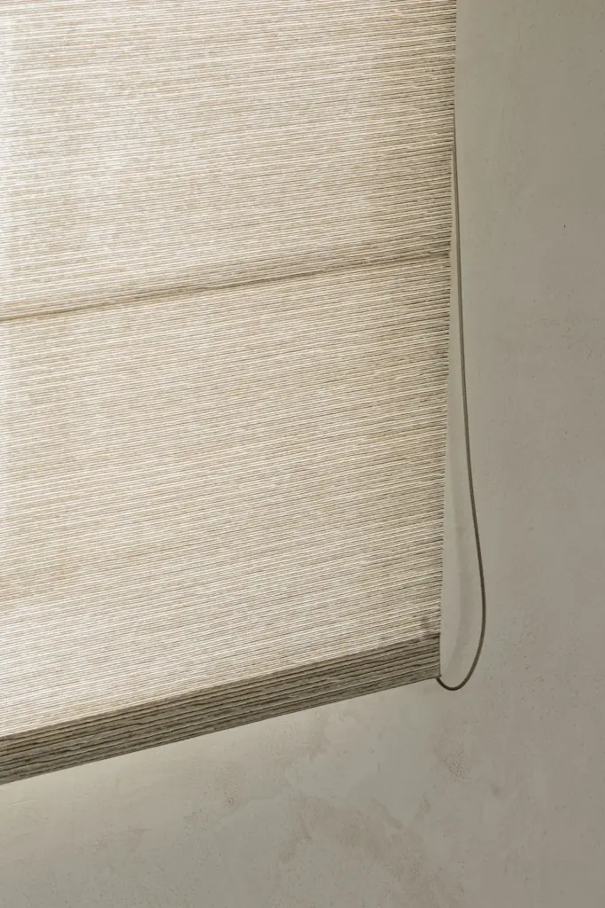 Detail van een rieten roman blind tegen een gepleisterde wand, a masterful balance between authenticity and comfort, interieur Laura Calleeuw