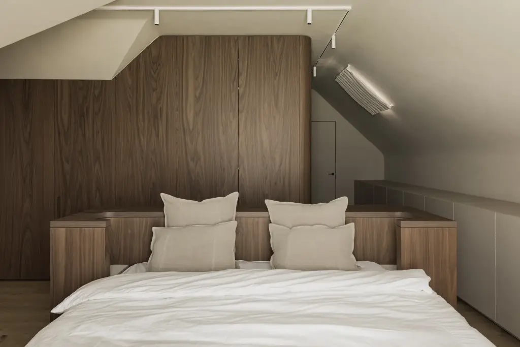 Slaapkamer onder de dakhelling met notelaren wand, bed met linnen kussens en een leeslamp, a masterful balance between authenticity and comfort, interieur Laura Calleeuw