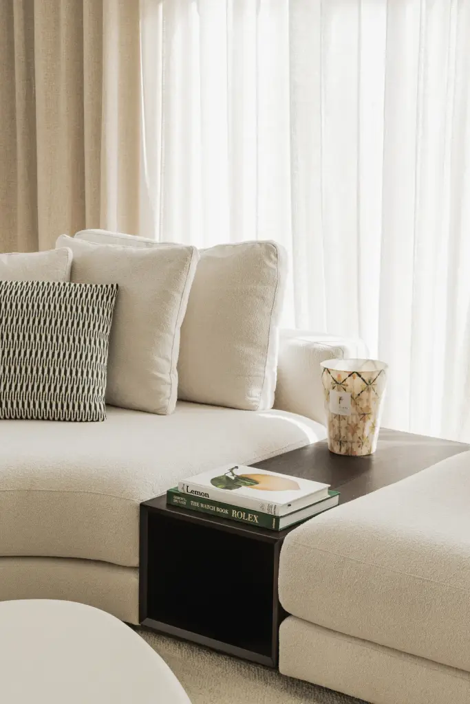 Sofa met kussens en een zwarte bijzettafel met boek naast de salontafel, a masterful balance between authenticity and comfort, interieur Laura Calleeuw