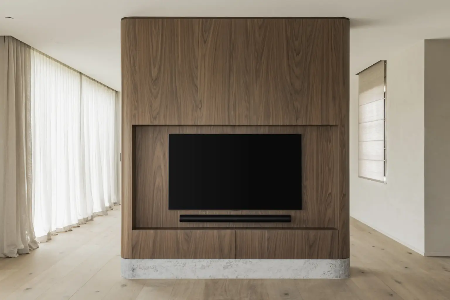 Televisie in een notelaren volume met natuurstenen plint voor een raam met gordijn, a masterful balance between authenticity and comfort, interieur Laura Calleeuw
