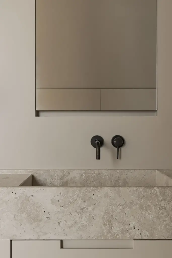 Natuurstenen wastafel met zwarte wandkranen onder een spiegelkast, a masterful balance between authenticity and comfort, interieur Laura Calleeuw