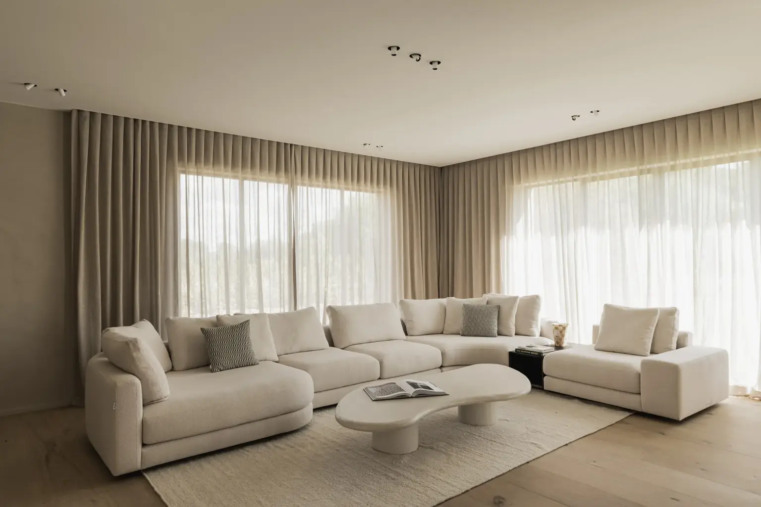 Leefruimte met hoeksofa, organische salontafel en lange gordijnen voor grote ramen, a masterful balance between authenticity and comfort, interieur Laura Calleeuw