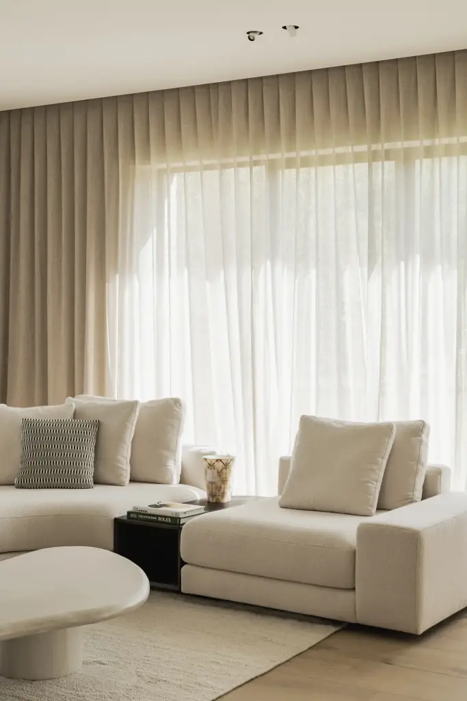 Zithoek met sofa, salontafel en gordijnen voor een groot raam, a masterful balance between authenticity and comfort, interieur Laura Calleeuw