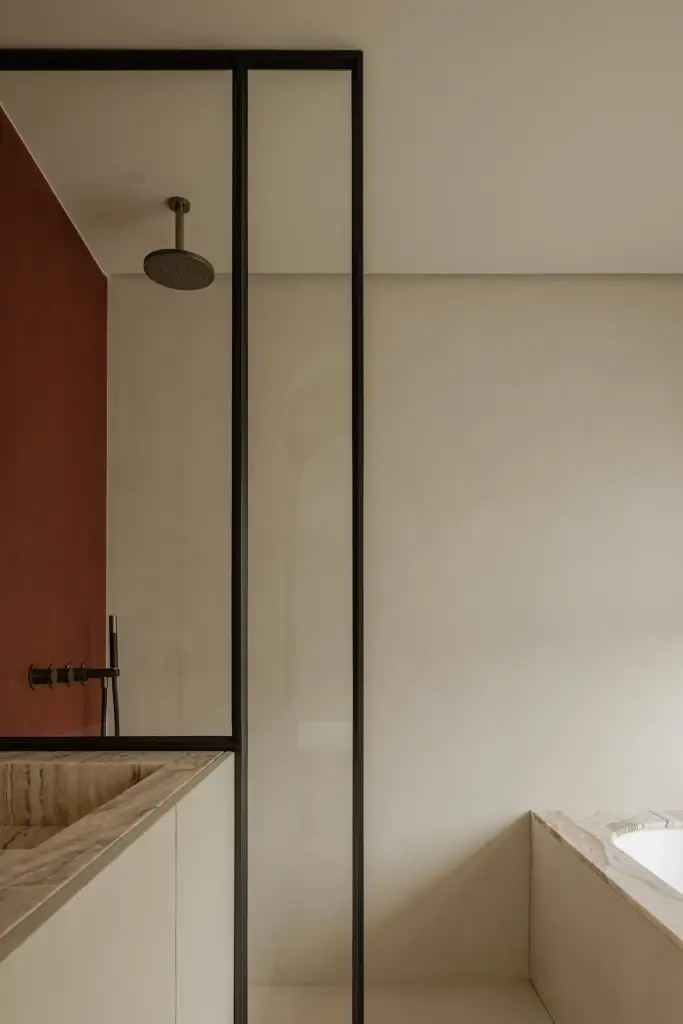 Badkamer met stalen glaswand, regendouche, terracotta wand en natuurstenen wastafel, Villarenovatie in Knokke, interieur Laura Calleeuw