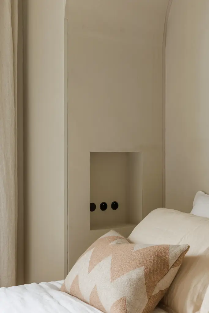 Bed met kussen en een nis met zwarte stopcontacten, Villarenovatie in Knokke, interieur Laura Calleeuw