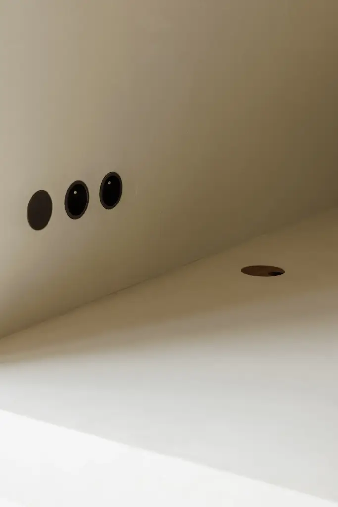 Bed met kussen en een nis met zwarte stopcontacten, Villarenovatie in Knokke, interieur Laura Calleeuw