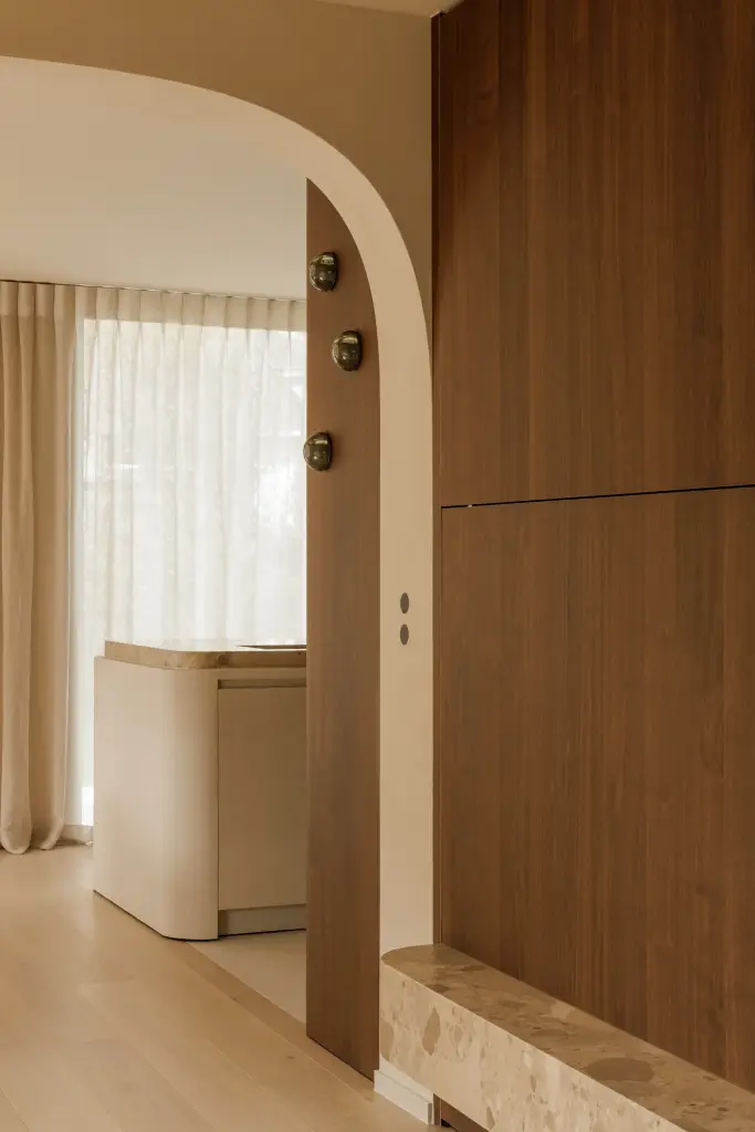 Boogopening naast een notelaren kast met doorkijk naar de keuken, Villarenovatie in Knokke, interieur Laura Calleeuw