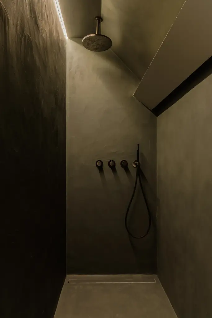 Douche met donkere kalkpleister, regendouche en zwarte thermostaatkranen, Villarenovatie in Knokke, interieur Laura Calleeuw