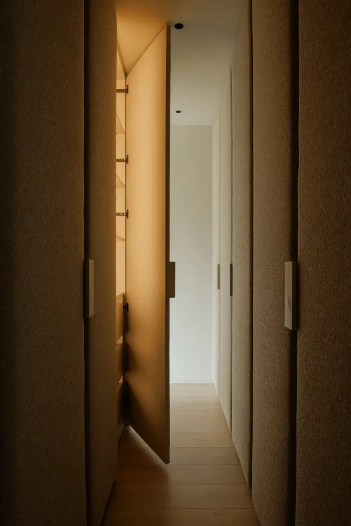 Garderobegang met warme verlichting en kasten in donker hout, Villarenovatie in Knokke, interieur Laura Calleeuw