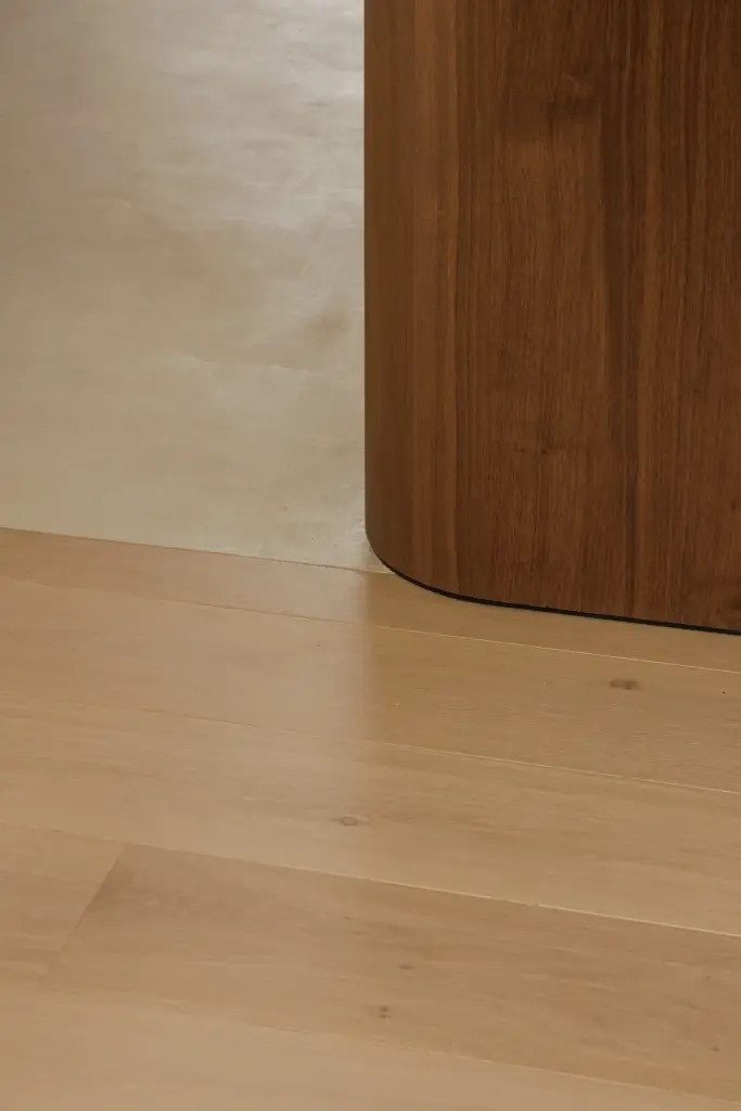 Detail van een gebogen notelaren wand op een eikenhouten vloer, Villarenovatie in Knokke, interieur Laura Calleeuw