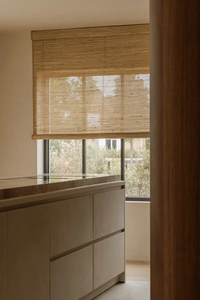 Keukenonderkasten voor een raam met roman blind naast een notelaren zijwand, Villarenovatie in Knokke, interieur Laura Calleeuw