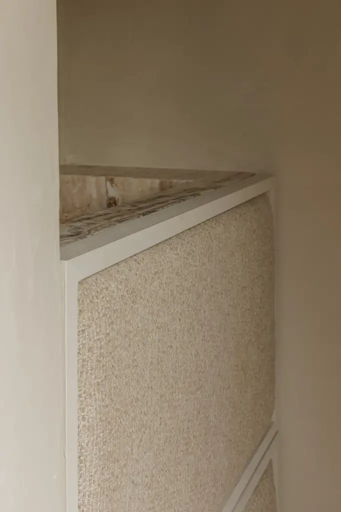 Detail van een hoek met natuurstenen plank en structuurpleister, Villarenovatie in Knokke, interieur Laura Calleeuw