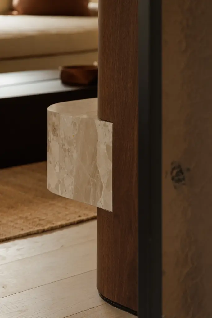 Natuurstenen bijzettafel naast een notelaren wand met houten schaal, Villarenovatie in Knokke, interieur Laura Calleeuw