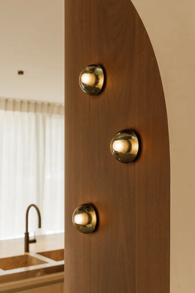 Notelaren boog met bronzen wandknoppen en een zwarte kraan op de achtergrond, Villarenovatie in Knokke, interieur Laura Calleeuw