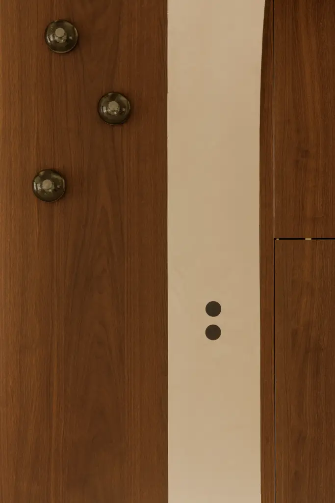 Detail van het notelaren paneel met bronzen knoppen en lichtschakelaars, Villarenovatie in Knokke, interieur Laura Calleeuw