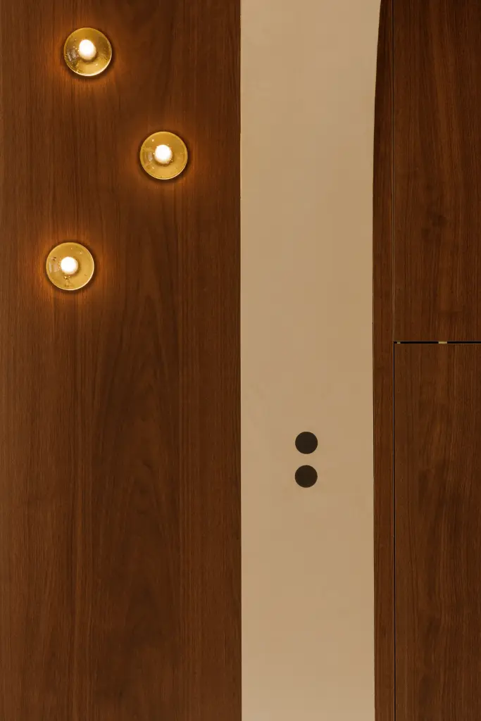 Detail van het notelaren paneel met bronzen knoppen en lichtschakelaars, Villarenovatie in Knokke, interieur Laura Calleeuw