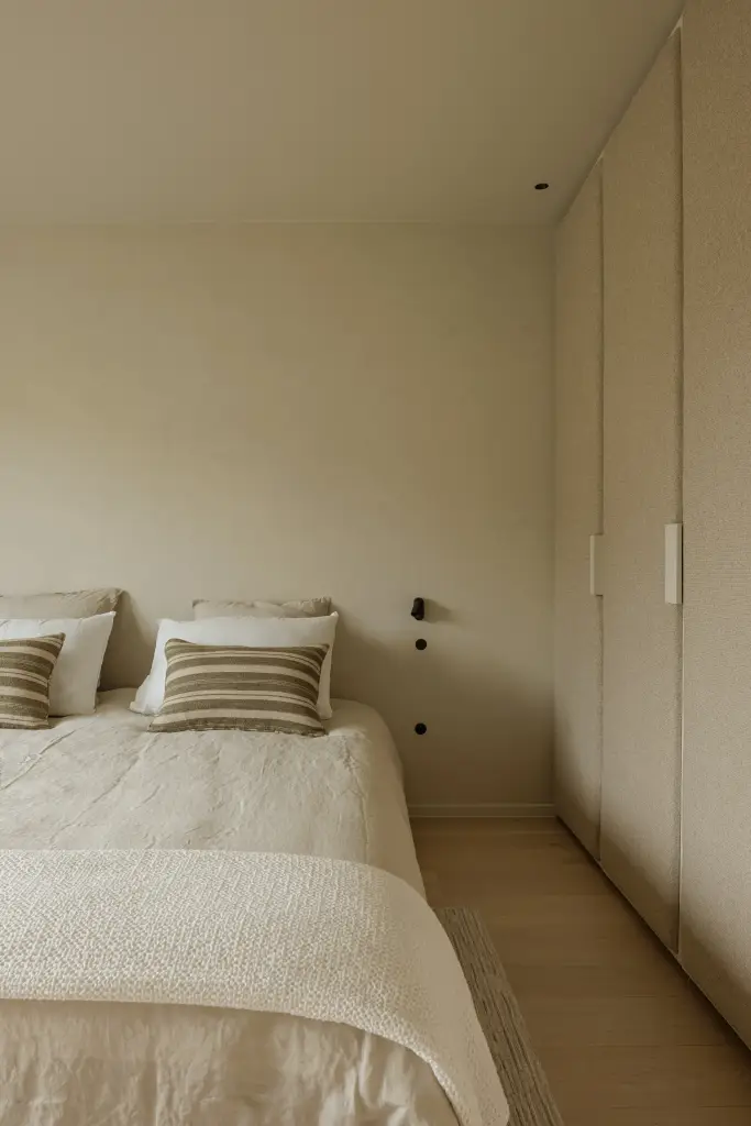 Bed met gestreepte kussens naast een kastenwand, Villarenovatie in Knokke, interieur Laura Calleeuw