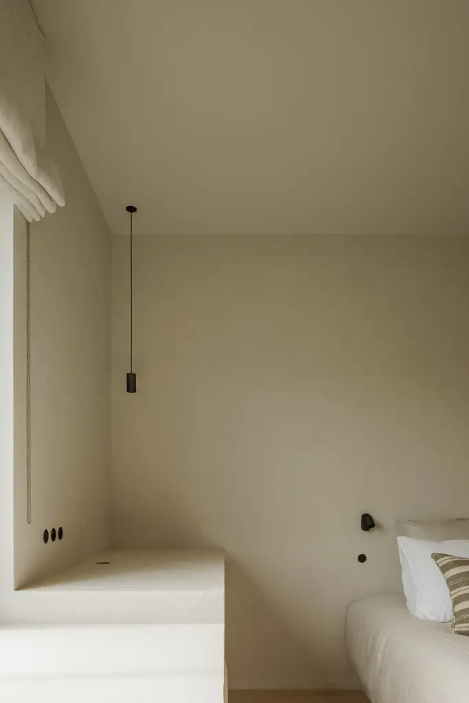 Slaapkamer met hanglamp boven het nachtkastje en bed met gestreept beddengoed, Villarenovatie in Knokke, interieur Laura Calleeuw