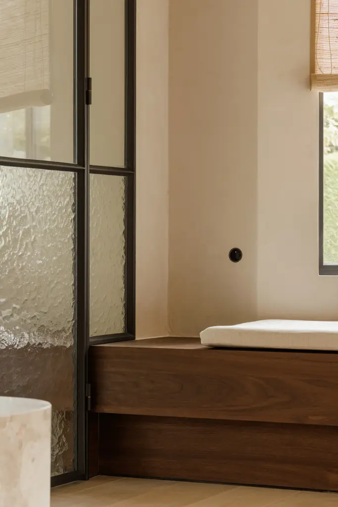 Stalen glasdeur met een notelaren bank en natuursteen, Villarenovatie in Knokke, interieur Laura Calleeuw
